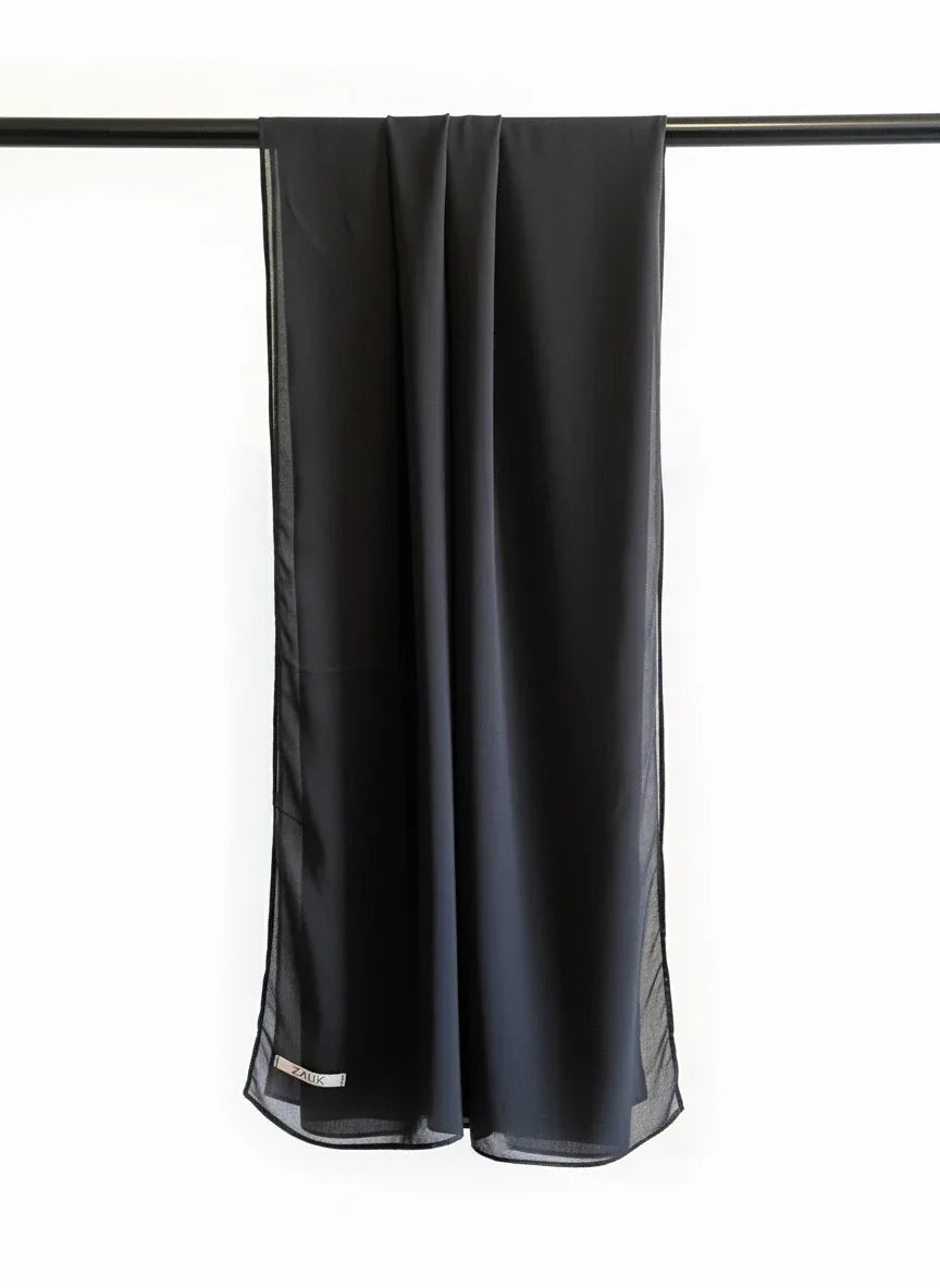 Black scarf hanging on a rod against a white background