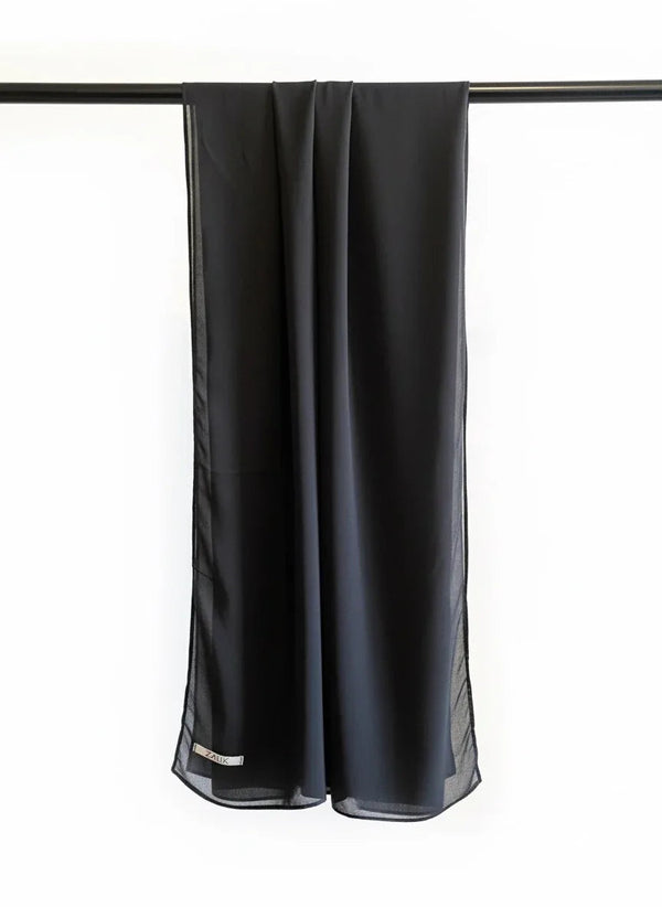 Black scarf hanging on a rod against a white background