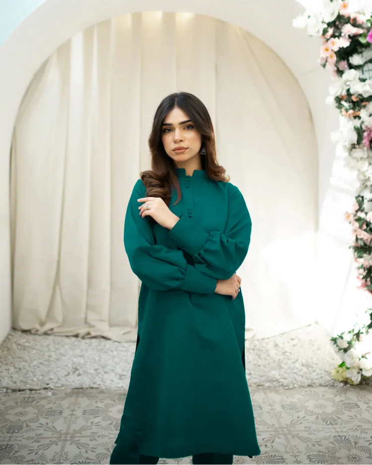 A woman wearing a green two-piece indian rawsilk dress consisting of a shirt and trousers.