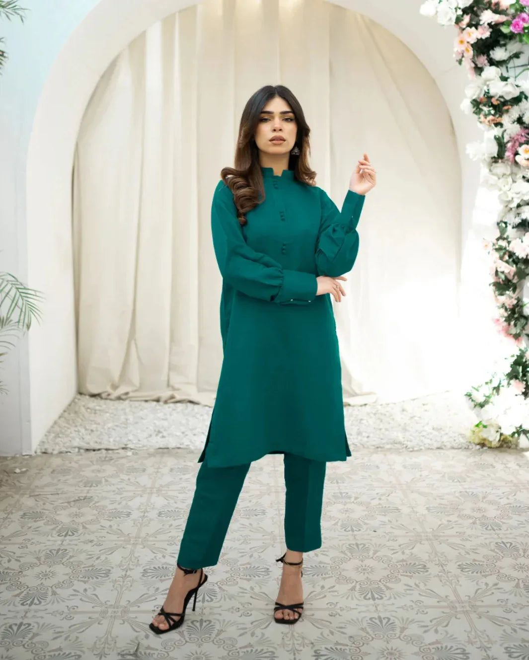 A woman wearing a green two-piece indian rawsilk dress consisting of a shirt and trousers.