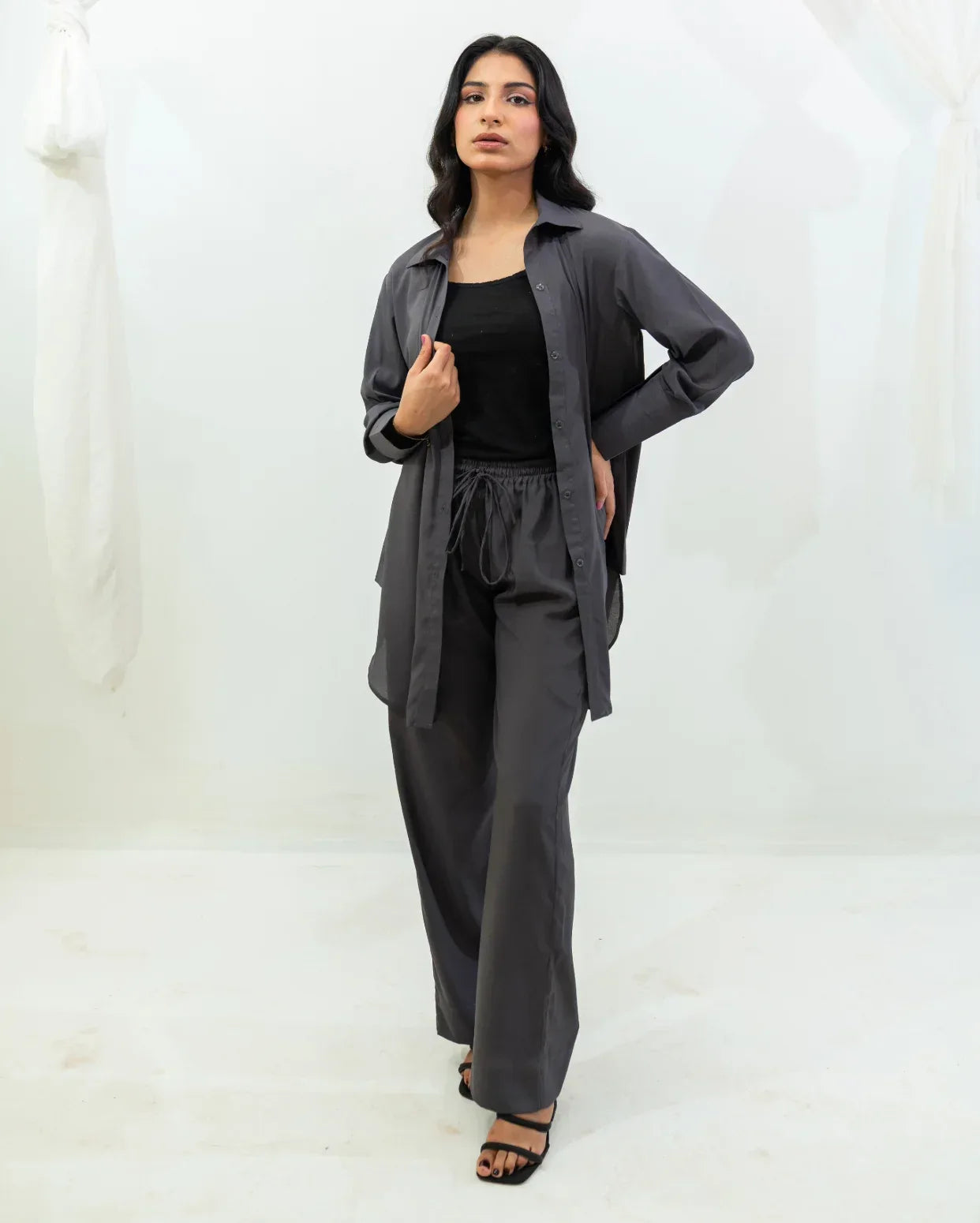 Woman wearing a charcoal gray outfit with a black top against a white background
