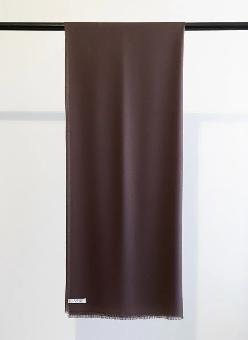 Brown scarf hanging on a black rod against a white background