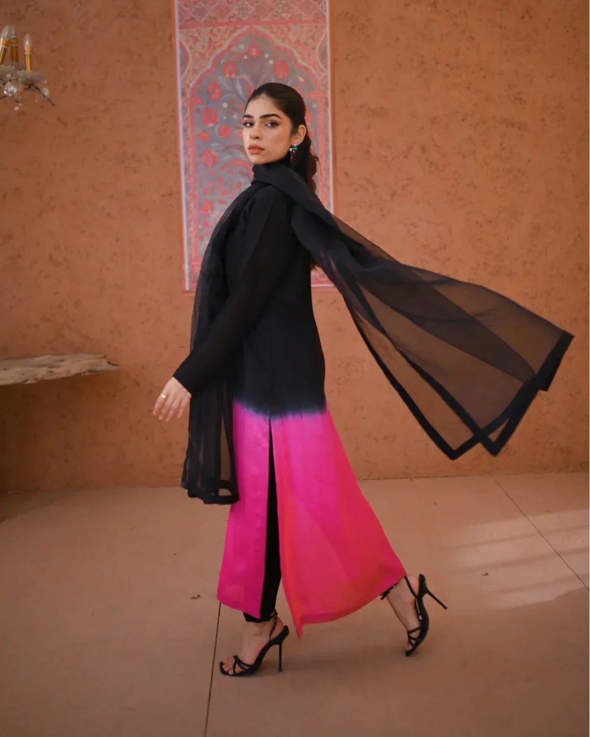 A woman wearing a three piece rawsilk dress with an ombre shirt and trousers, and an organza dupatta.