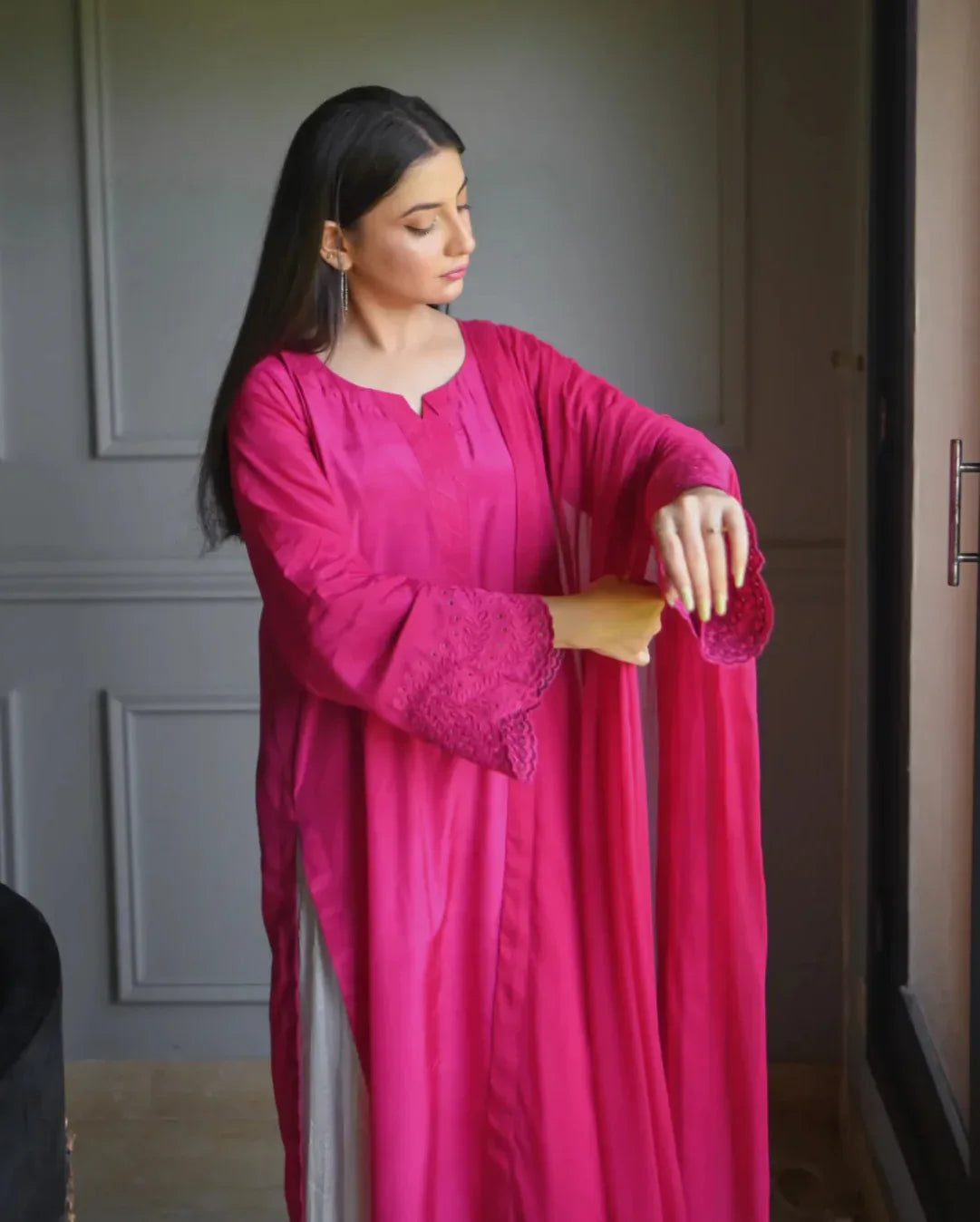 Women wearing a three piece pink color dress with embroidery on sleeves, and a chiffon dupatta.