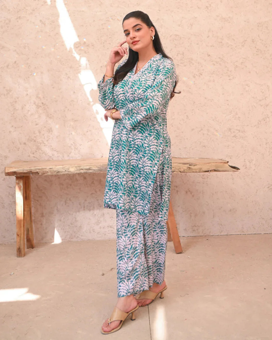 Women wearing a printed green and beige color two piece dress which includes a shirt and trouser.