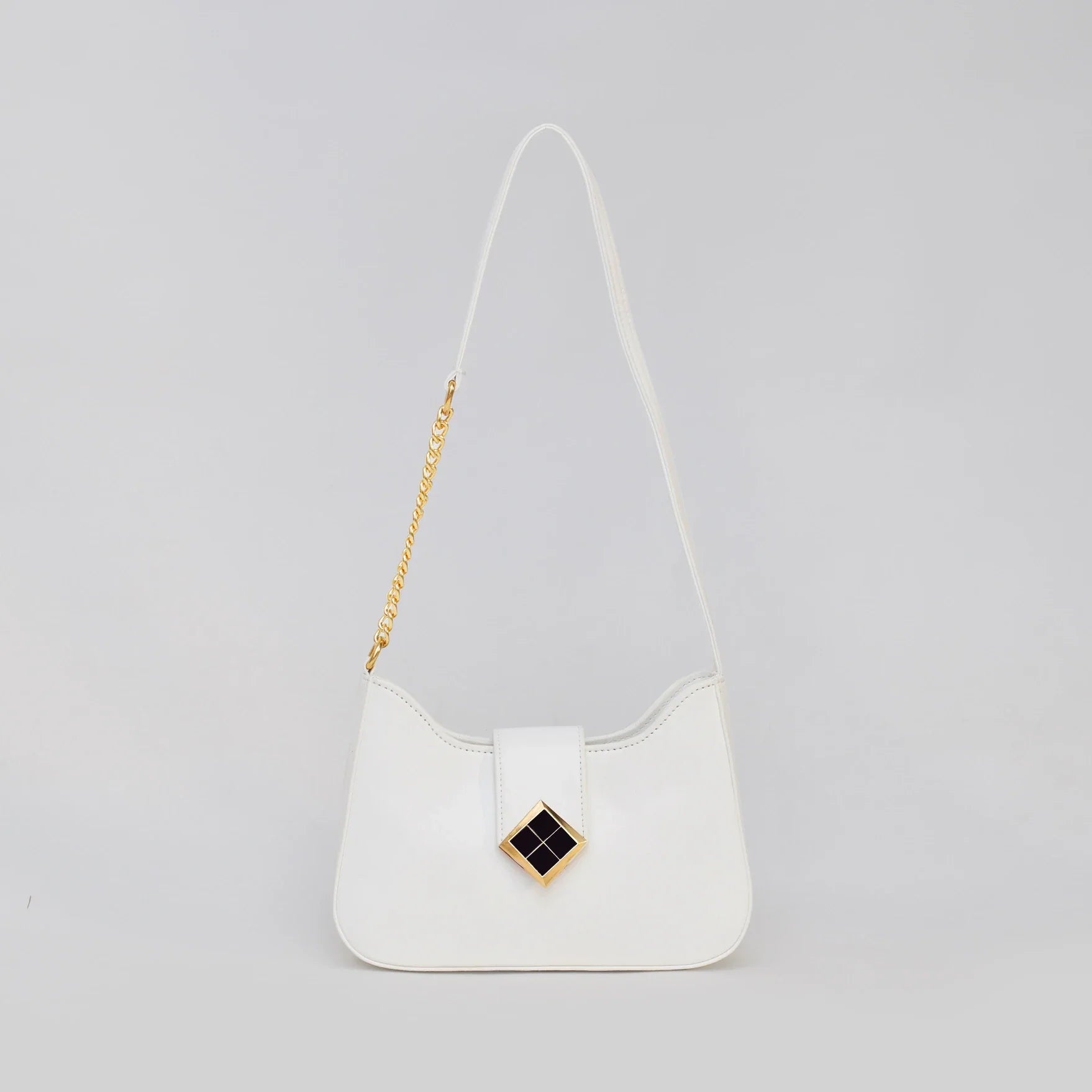 White handbag with a gold chain strap on a light gray background