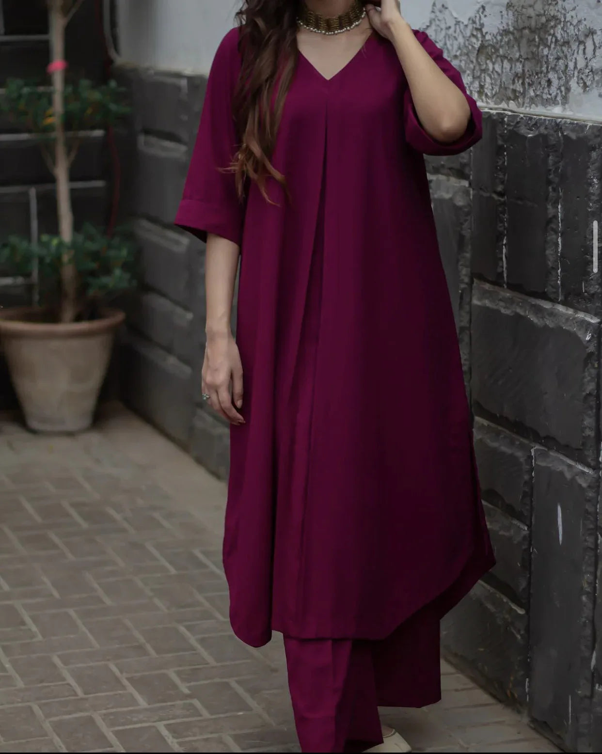 A woman in a magenta stitched dress standing confidently, showcasing her stylish outfit.