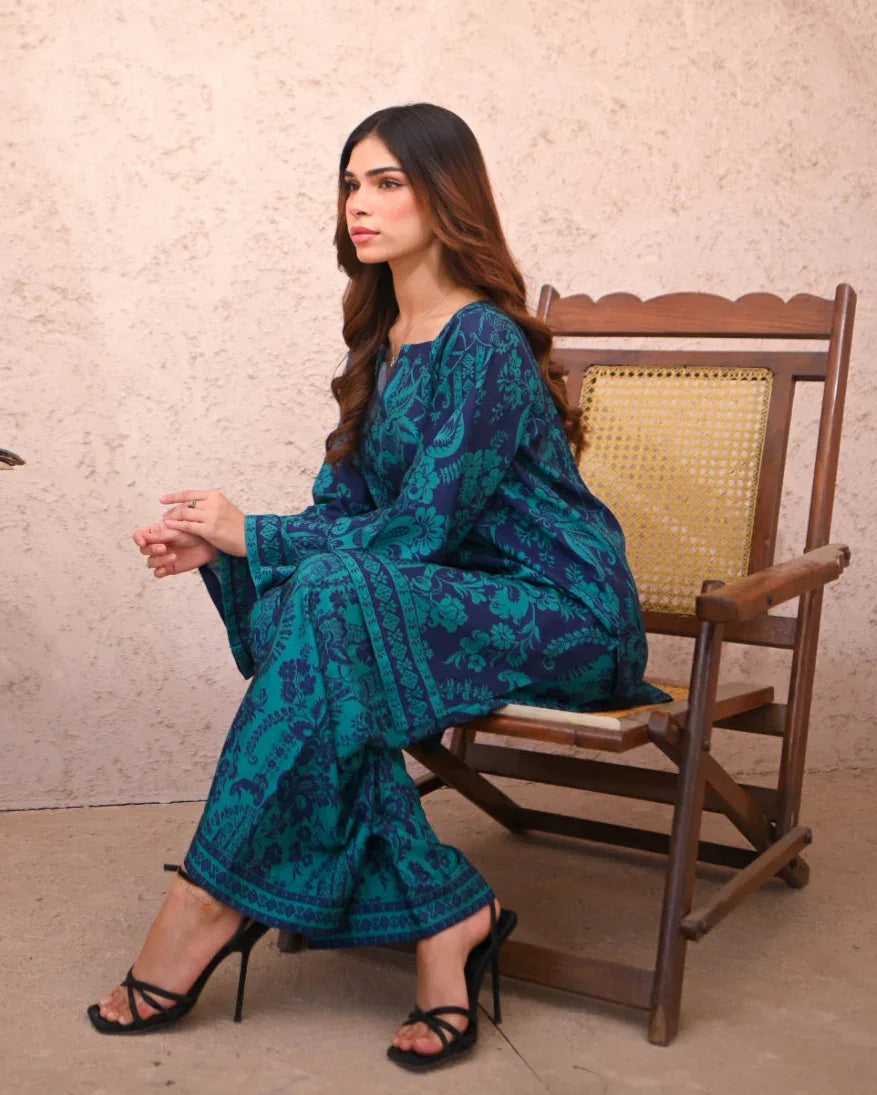 Women sitting on a chair wearing a floral printed two piece dress which includes a shirt and culotte.