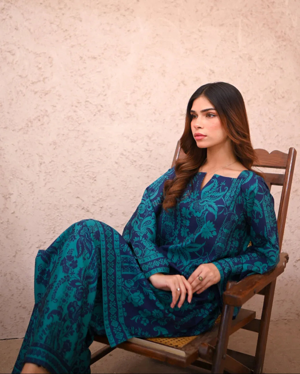 Women sitting on a chair wearing a floral printed two piece dress which includes a shirt and culotte.