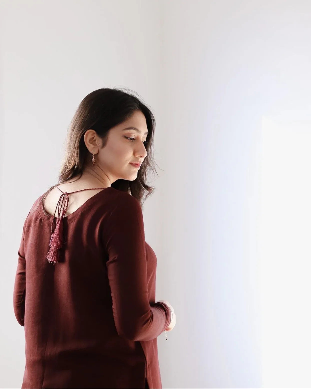 A women wearing a maroon two piece dress with a resham dori on the back.