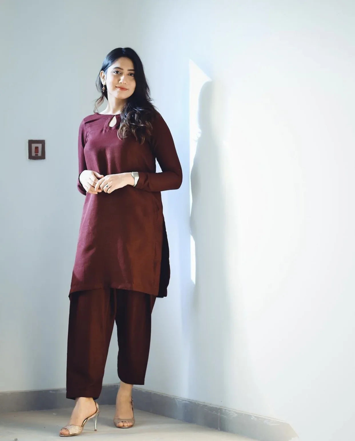 A women wearing a maroon two piece dress which includes a shirt and culotte.