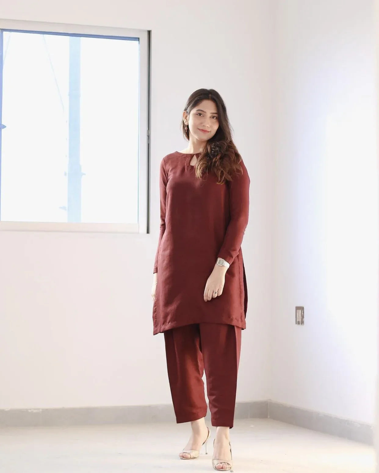 A women wearing a maroon two piece dress which includes a shirt and culotte.