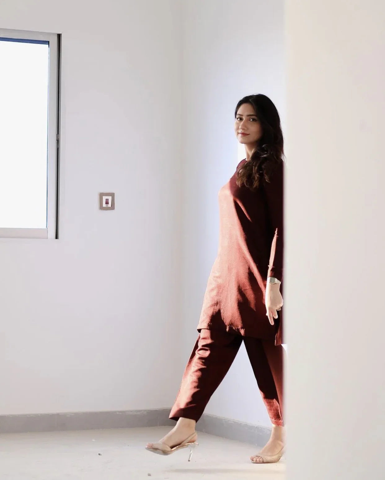 A women wearing a maroon two piece dress which includes a shirt and culotte.