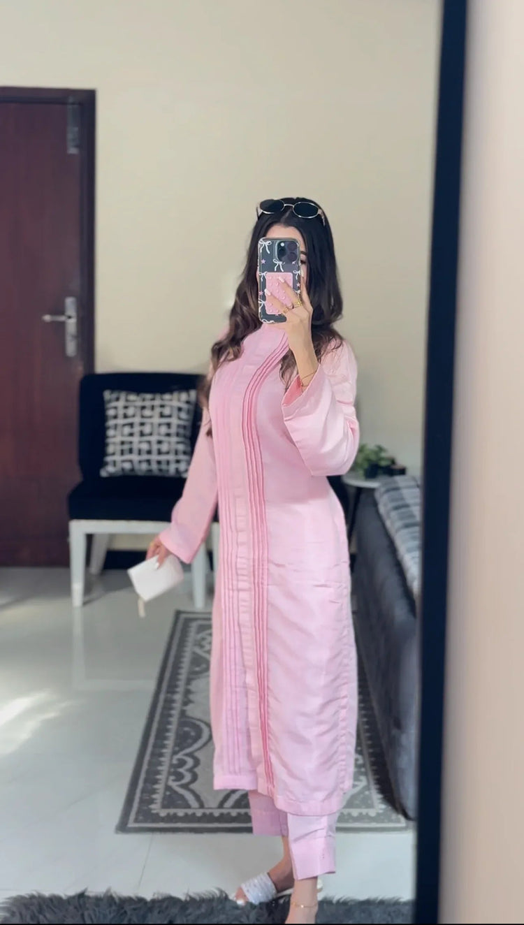 A women wearing a pink outfit in a room with a chair and door.