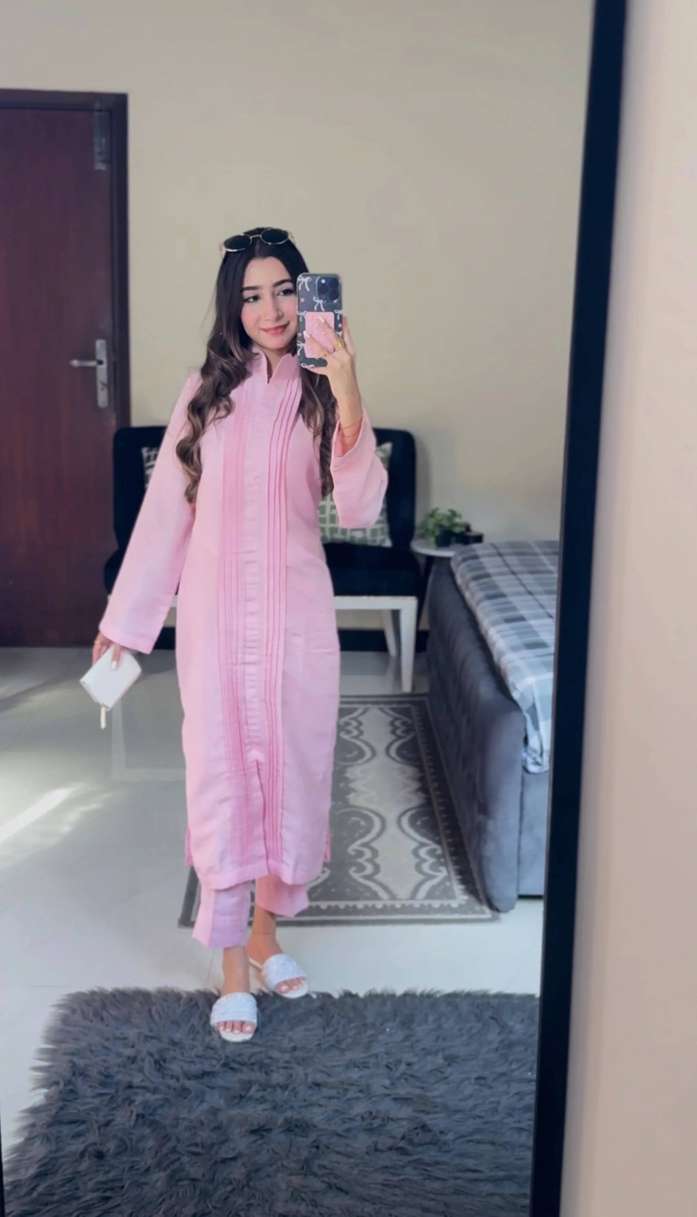 Person wearing a pink outfit taking a mirror selfie in a room.