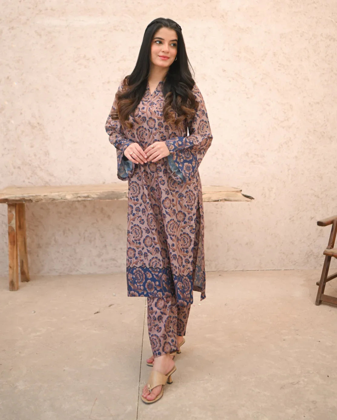 A Women wearing a printed brown and navy blue color two piece dress which includes a shirt and a culotte. Print is floral.