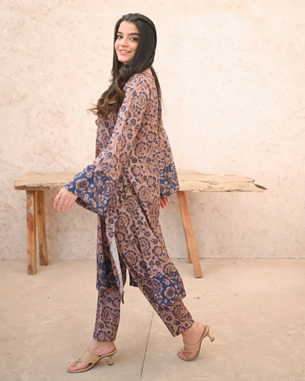 A Women wearing a printed brown and navy blue color two piece dress which includes a shirt and a culotte. Print is floral.