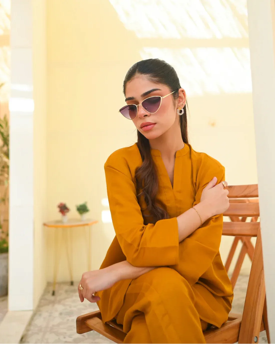 A woman wearing a mustard yellow two-piece dress with long sleeves, consisting of a shirt and trousers.