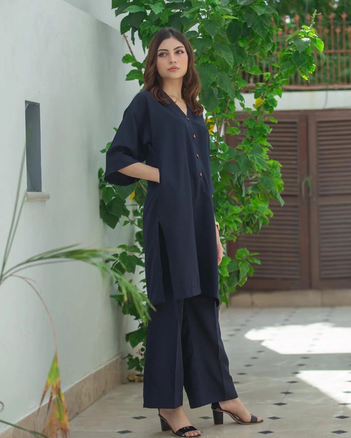 Woman in a navy blue Dress standing outdoors with greenery in the background