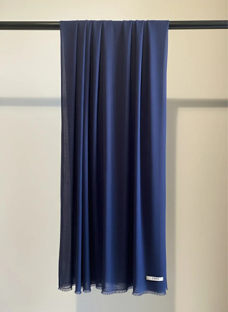 Navy blue scarf hanging on a rod against a neutral background