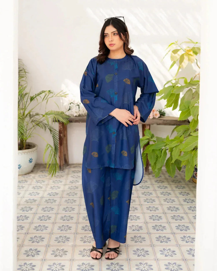 Woman wearing a navy blue traditional printed in a room with plants and a tiled floor.