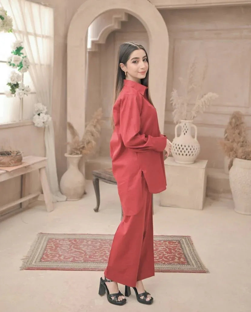 A woman in red dress stands confidently in a well-lit room, surrounded by neutral-colored walls and furniture.