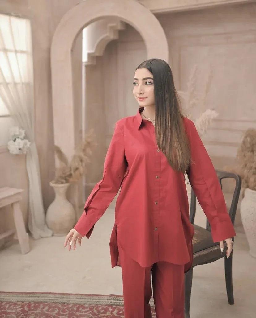 A woman in red dress stands confidently in a well-lit room, surrounded by neutral-colored walls and furniture.