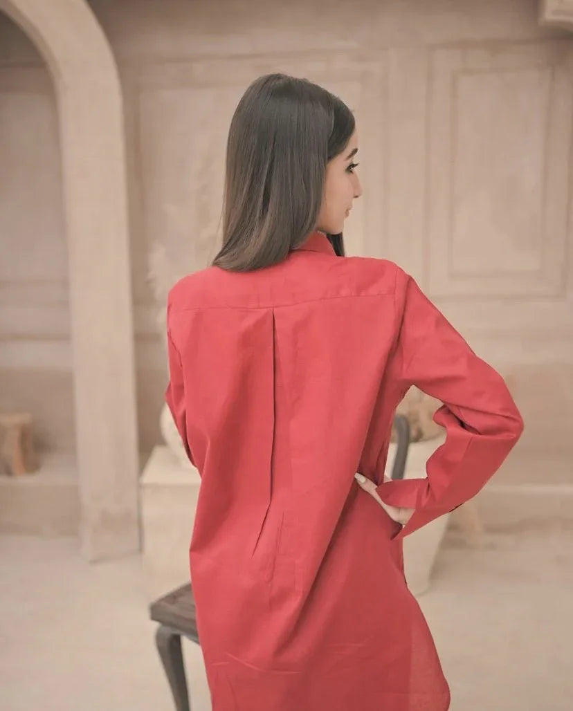 A woman in red dress standing in a well-lit room, surrounded by neutral-colored walls and furniture.